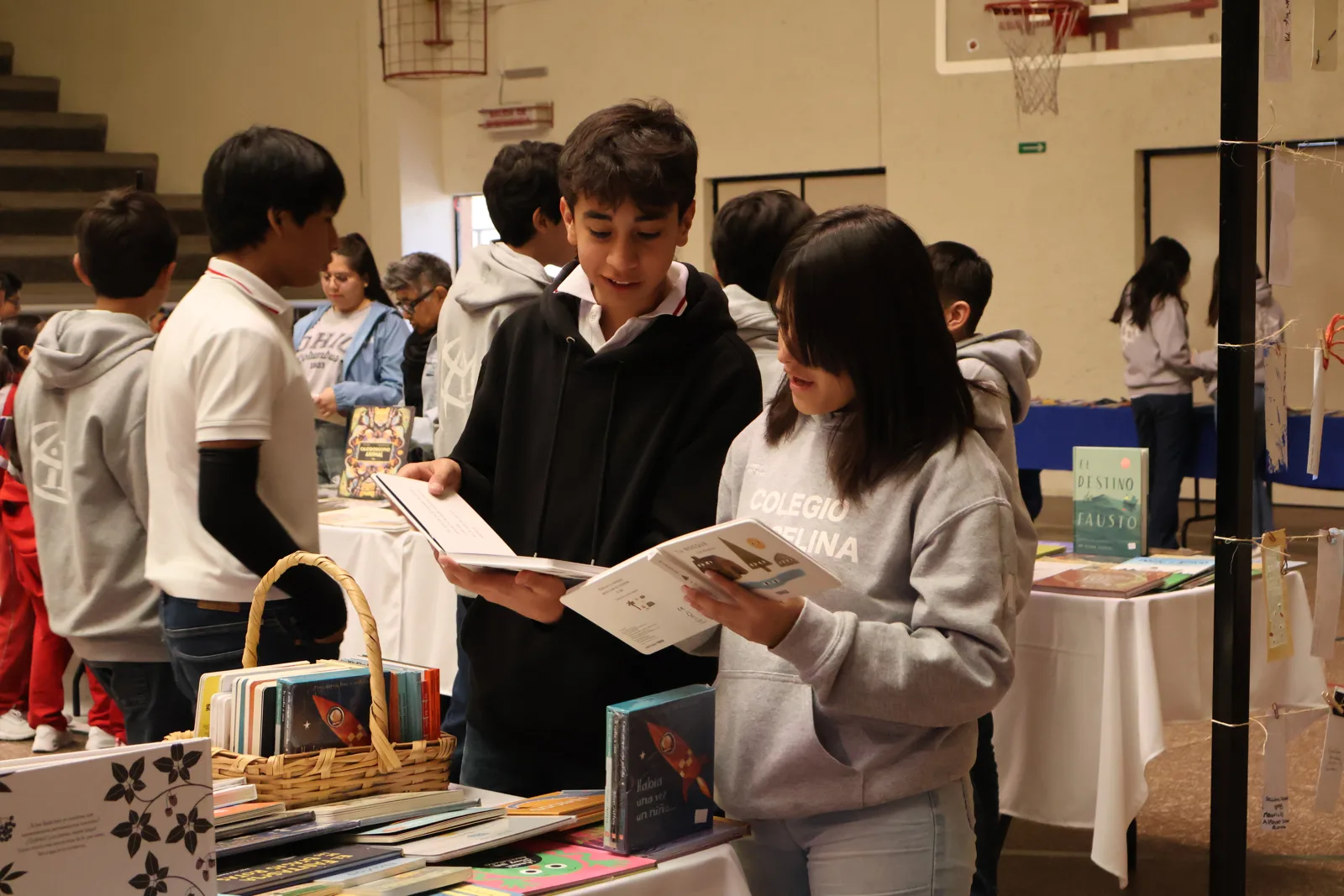 Estudiantes de secundaria explorando libros en la feria de la biblioteca del Colegio Marcelina
